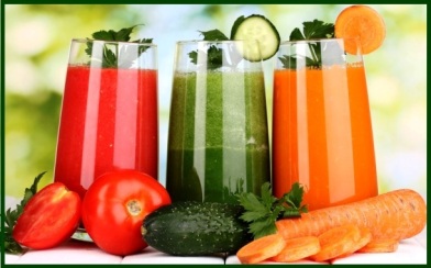 Fresh vegetable juices on wooden table, on green background